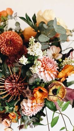 an arrangement of flowers and greenery on a white tablecloth with text overlay