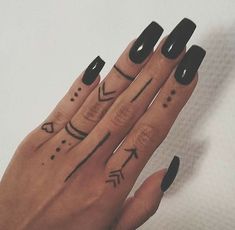 a woman's hand with black nail polish and arrows on her fingers, which are drawn in cursive lines