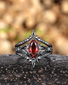 a close up of a ring with a red stone in the center on a rock