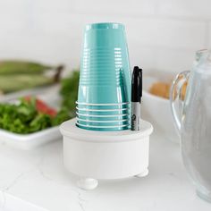 a stack of blue cups sitting on top of a counter next to a salad bowl