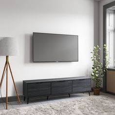 a flat screen tv mounted to the side of a wall next to a wooden floor lamp