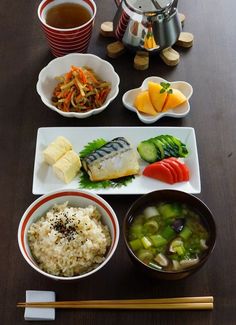 a table topped with bowls of food and chopsticks on top of a wooden table