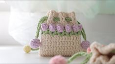 a crocheted purse sitting on top of a white table next to some flowers