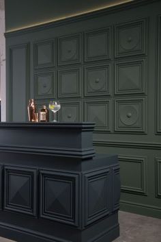 a black bar with two bottles on top and some glasses sitting on the counter next to it