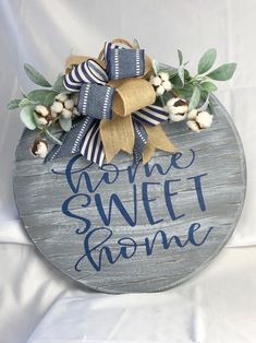 a wooden sign that says come sweet home with cotton flowers and greenery on it