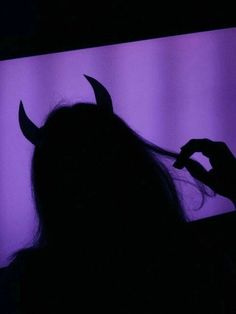 the silhouette of a woman with horns on her head is shown in front of a purple background