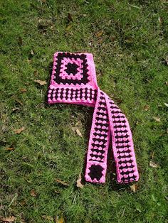 two pink and black crocheted squares laying on the grass