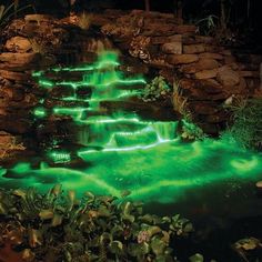 a garden with green lights on the ground and water running down it's sides