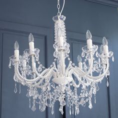 a white chandelier hanging from the ceiling in a room with blue walls and doors