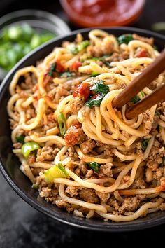 a black bowl filled with noodles and meat