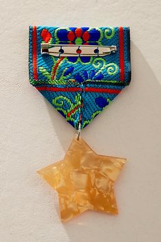 a star shaped brooch hanging from the side of a wall next to a piece of fabric