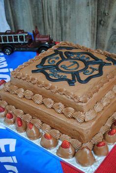 a large cake with chocolate frosting and strawberries on the bottom is sitting on a table