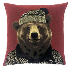 a brown bear wearing a knitted hat on top of a red pillow with a black and white sweater