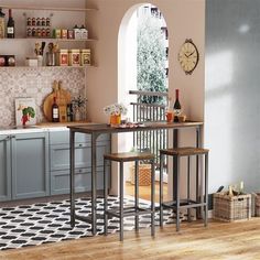 a kitchen with two stools and a table in front of the window, next to an open door