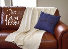 a brown leather couch with a blue and white throw blanket on it's back