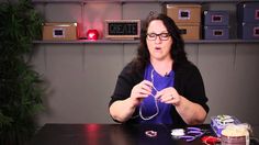 a woman sitting at a table with some wires in her hands