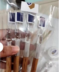 a person holding up some wooden toothbrushes with pictures on the top of them