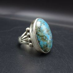 "PAUL LIVINGSTON NAVAJO BLUE MOON TURQUIOSE RING DESCRIPTION: This ring features a glorious specimen of Blue Moon turquoise. The gemstone is secure in smooth bezel, on a foundation of heavy gauge sterling silver. The substantial split-shank band is punctuated with applied raindrops. This ring will be a treasured addition to your collection of fine Native American jewelry. MEASUREMENTS: Ring face measures 1\" x 3/4\" Cabochon measures 25mm x 18mm RING SIZE: 8 1/4 WEIGHT: 12. grams SIGNED: Paul Li Blue Sterling Silver Ring With Patina, Blue Sterling Silver Rings With Patina, Vintage Blue Cabochon Ring, Vintage Turquoise Ring With Large Stone, Heirloom Blue Oval Cabochon Turquoise Ring, Blue Oval Cabochon Collectible Rings, Vintage Oval Turquoise Ring, Vintage Blue Ring With Large Stone, Unique Oval Ring With Patina