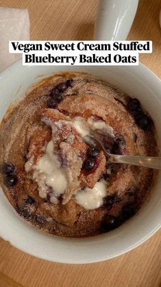 a bowl of oatmeal with blueberries and cream in it on a wooden table