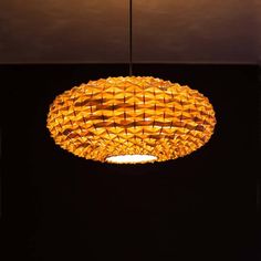 a yellow light hanging from the ceiling in a room with black walls and flooring