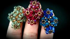 three different colored rings sitting on top of each other in their hands with gold and blue beads