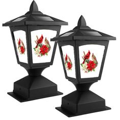 two black lanterns with red and white flowers painted on the front, one has a humming perched on it