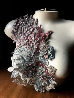 a mannequin is adorned with an intricately detailed piece of fabric and beads