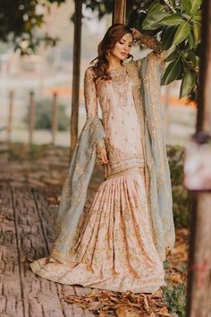 a woman in a long dress standing under a tree