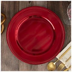 a red plate sitting on top of a wooden table next to gold utensils