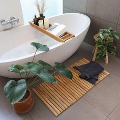 a bathroom with a bathtub, plants and towels on the floor next to it