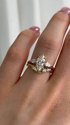 a woman's hand wearing a gold ring with two diamonds on it and a star shaped diamond in the middle