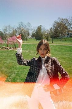 a woman standing in the grass with her hand up