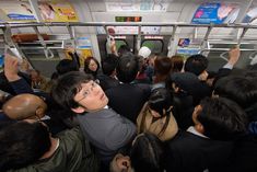 a group of people standing on a subway train looking up at something in the air