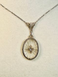 This beautiful camphor glass and diamond necklace features a sunburst design in frosted glass with a diamond in the center. The diamond is in a diamond shaped setting. The white gold surrounding is done in filigree and is very delicate. There is an integral chain attached. The necklace is approximately 9.5 inches long. The pendant measures about 4.5 cm x 2 cm including the bail. The necklace is in excellent antique condition. Total weight 5.3g. Display boxes: Boxes pictured are not for sale and Victorian Pendant Necklace, Victorian Jewellery, Sparkly Things, Art Deco Necklace, Gold Filigree, Diamond Shaped, Display Boxes, Antique Jewellery, Frosted Glass