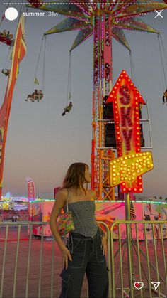 a woman standing in front of a carnival ride