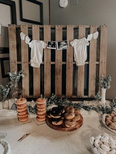 a table topped with lots of donuts next to wooden crates filled with baby clothes