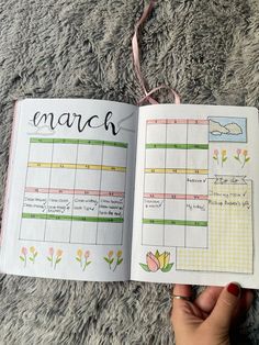 a hand holding an open planner book on top of a carpet