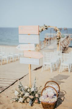 a sign that is sitting in the sand with flowers and blankets on top of it