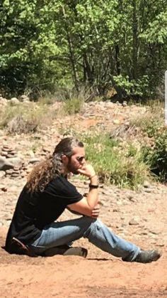 a man sitting on the ground next to a sign