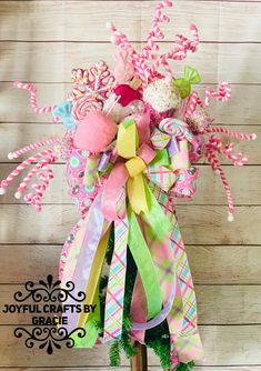 a pink, green and white bow with candy canes in it on a stick