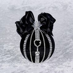 a black and white purse with a bow on the front, decorated with crystals and pearls