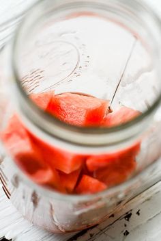 a jar filled with watermelon slices sitting on top of a wooden table