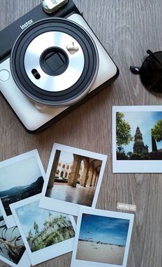 polaroid camera sitting on top of a wooden table next to pictures and other items