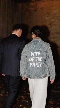 a man in a suit and tie walking next to a woman wearing a denim jacket with the words wife of the party written on it