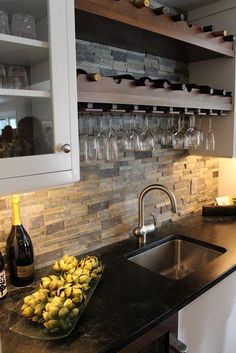 a kitchen counter top with wine glasses on it and bottles in the back drop off