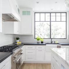 a kitchen with white cabinets and black counter tops, along with an island in the middle