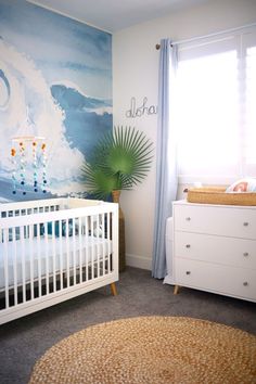 a baby's room with a crib, dresser and large painting on the wall