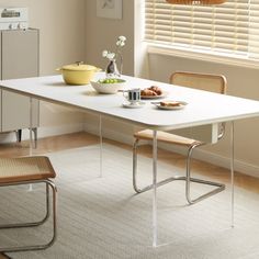 a white table with two chairs and a bowl of food on it in front of a window