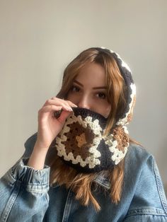 a woman wearing a crocheted scarf covering her face