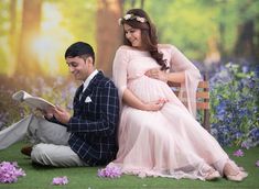 a pregnant couple sitting on a bench in front of a wall with bluebells